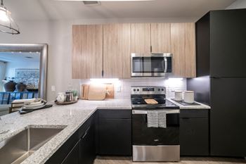 a kitchen with black appliances and granite counter tops at Station at Old Town, Texas, 75057